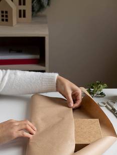 Frau im weißen Pulli packt Geschenk für den Weihnachtsbasar ein