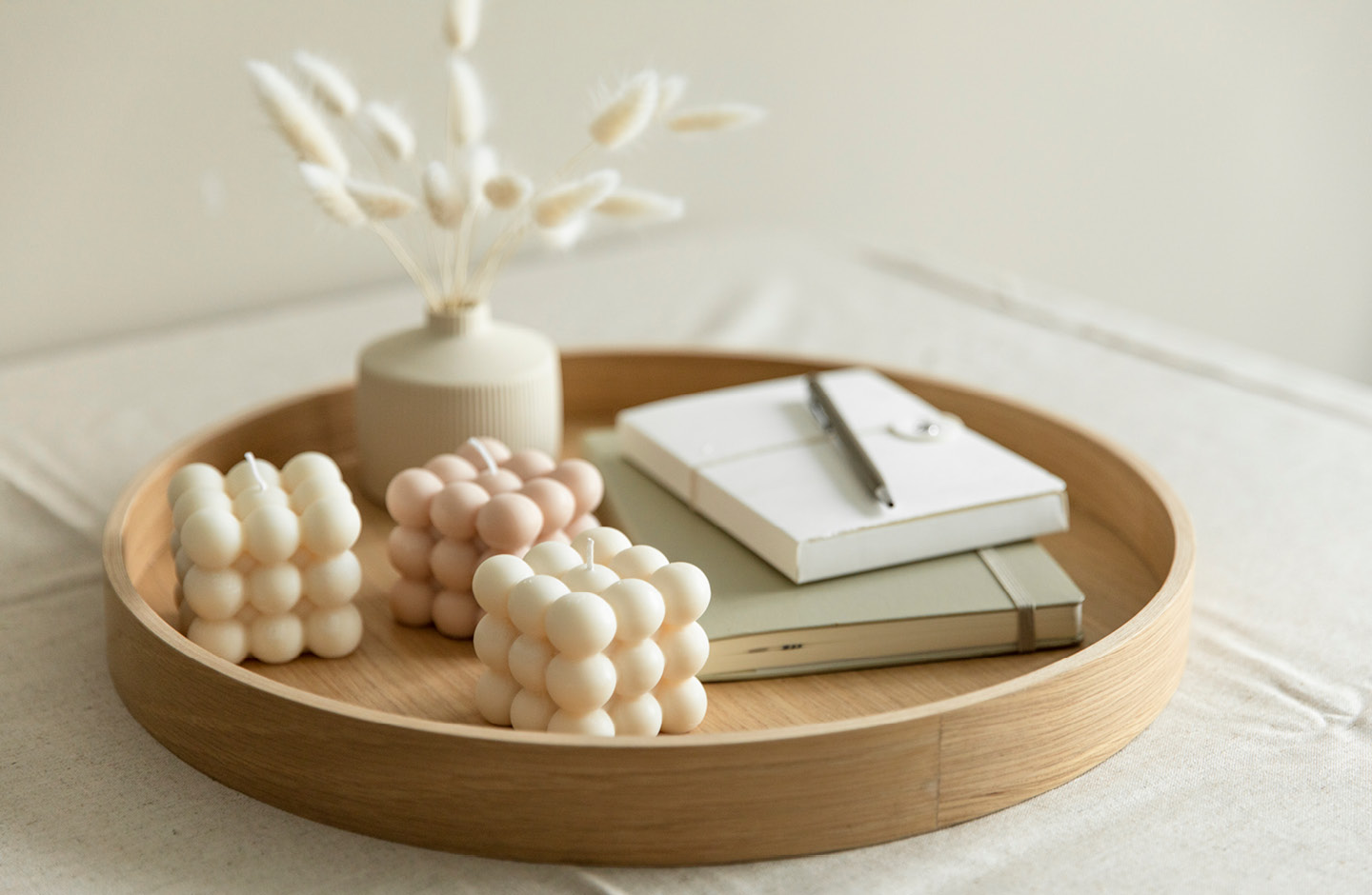 DIY-Bubblekerzen auf Holztablett mit Vase und Notizbüchern