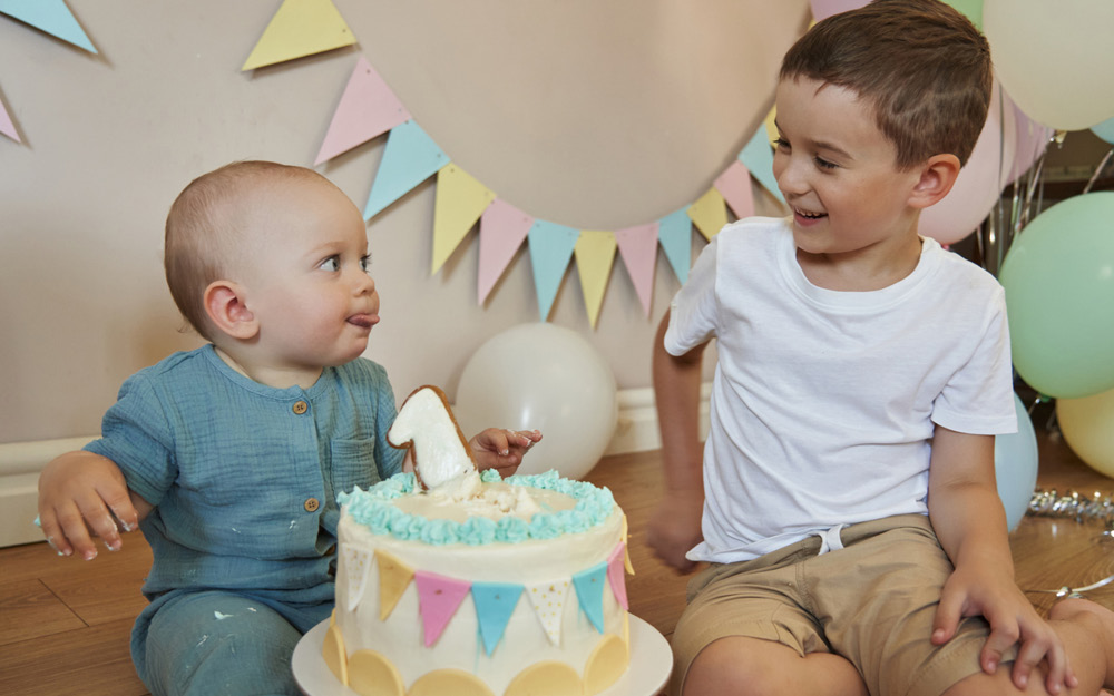 1 jähriges Baby streckt an seinem Geburtstag seinem Bruder die Zunge raus.