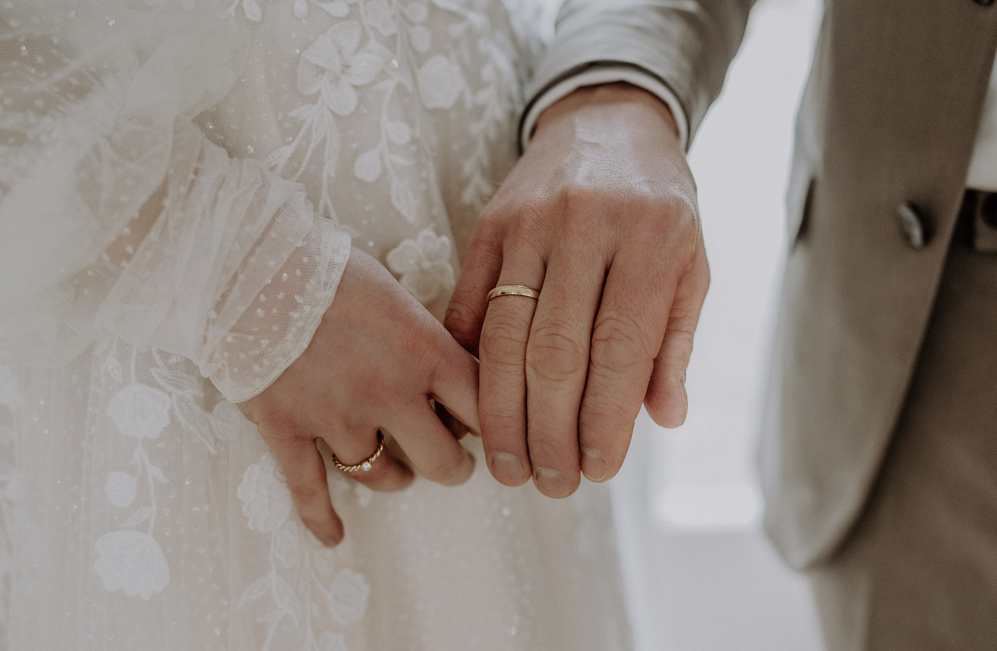 Hände von Braut und Bräutigam, mit goldenen Ringen an den Ringfingern