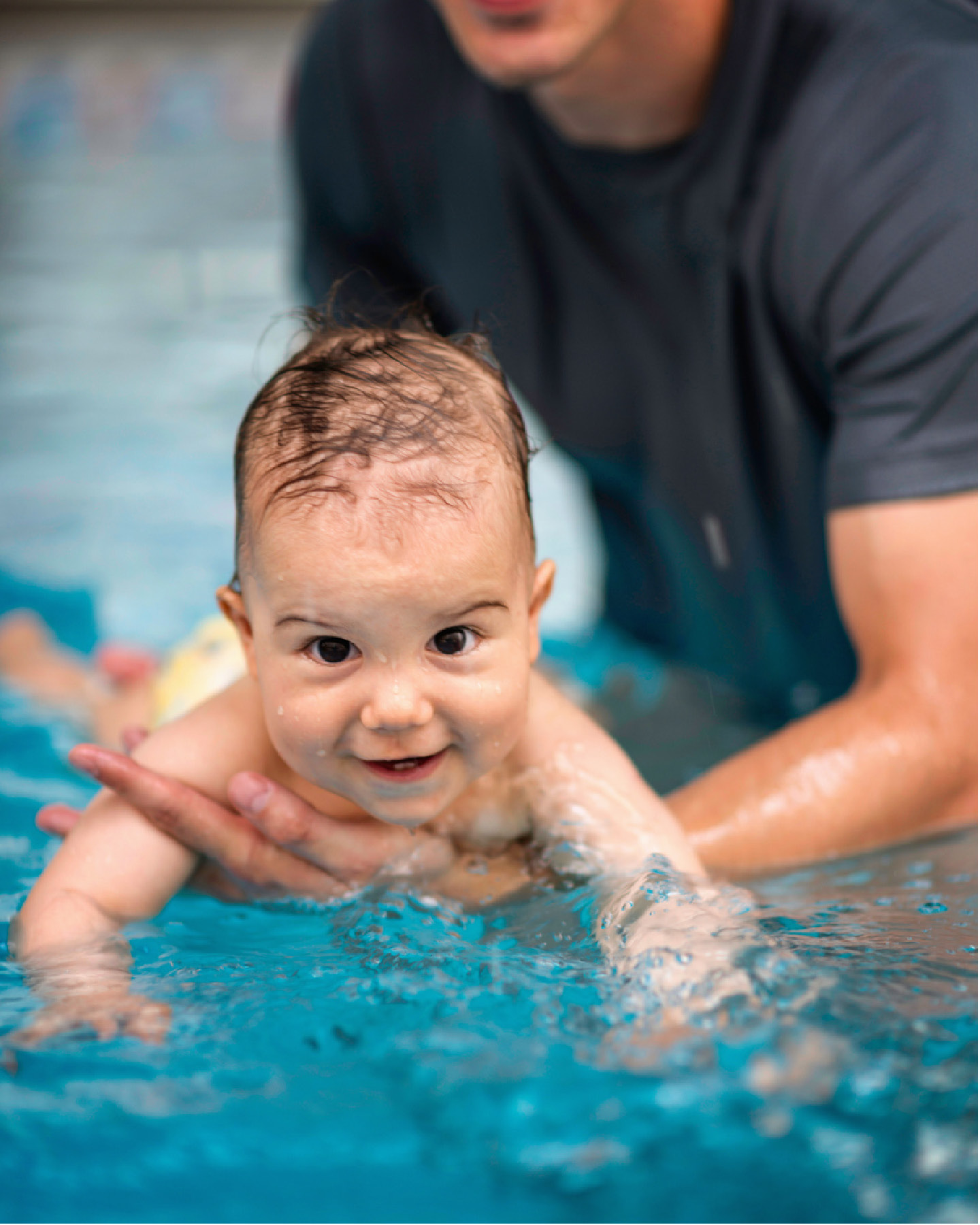 Schwimmeister mit Baby beim Babyschwimmen