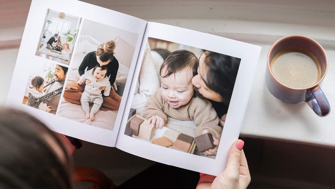 Mama schaut im Fotobuch die schönsten Familienmomente an.