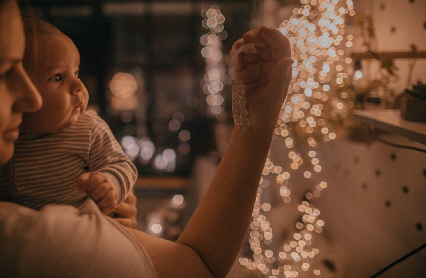 Mutter mit Baby auf dem Arm bei stimmungsvoller Beleuchtung zur Weihnachtszeit