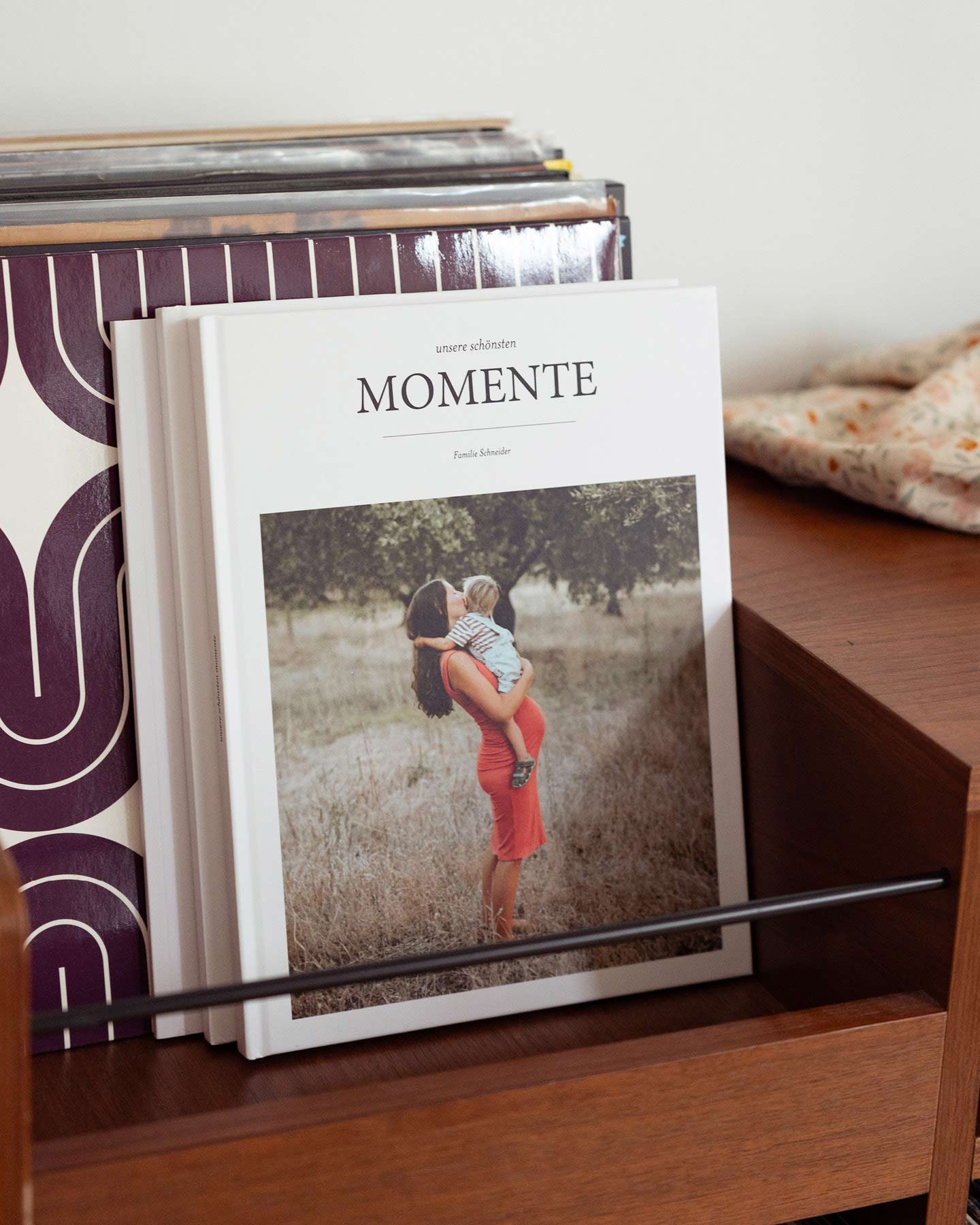 Fotobücher mit den schönsten Moment einer Familie stehen in einem Holzreal