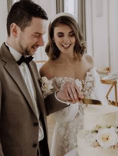 Glückliches Brautpaar schneidet nach der Trauung auf dem Standesamt die Hochzeitstorte an