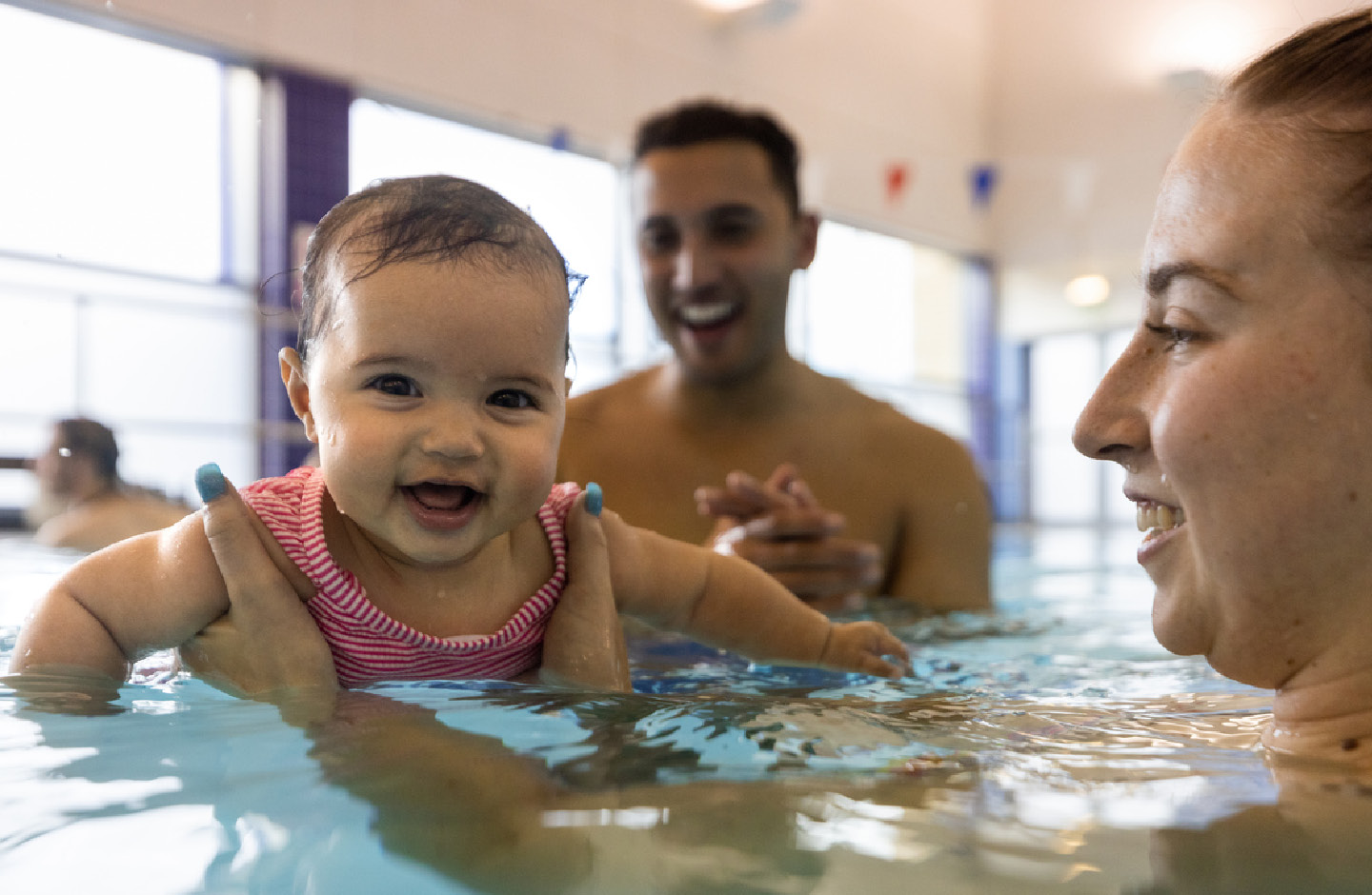 Baby mit Eltern beim Babyschwimmkurs